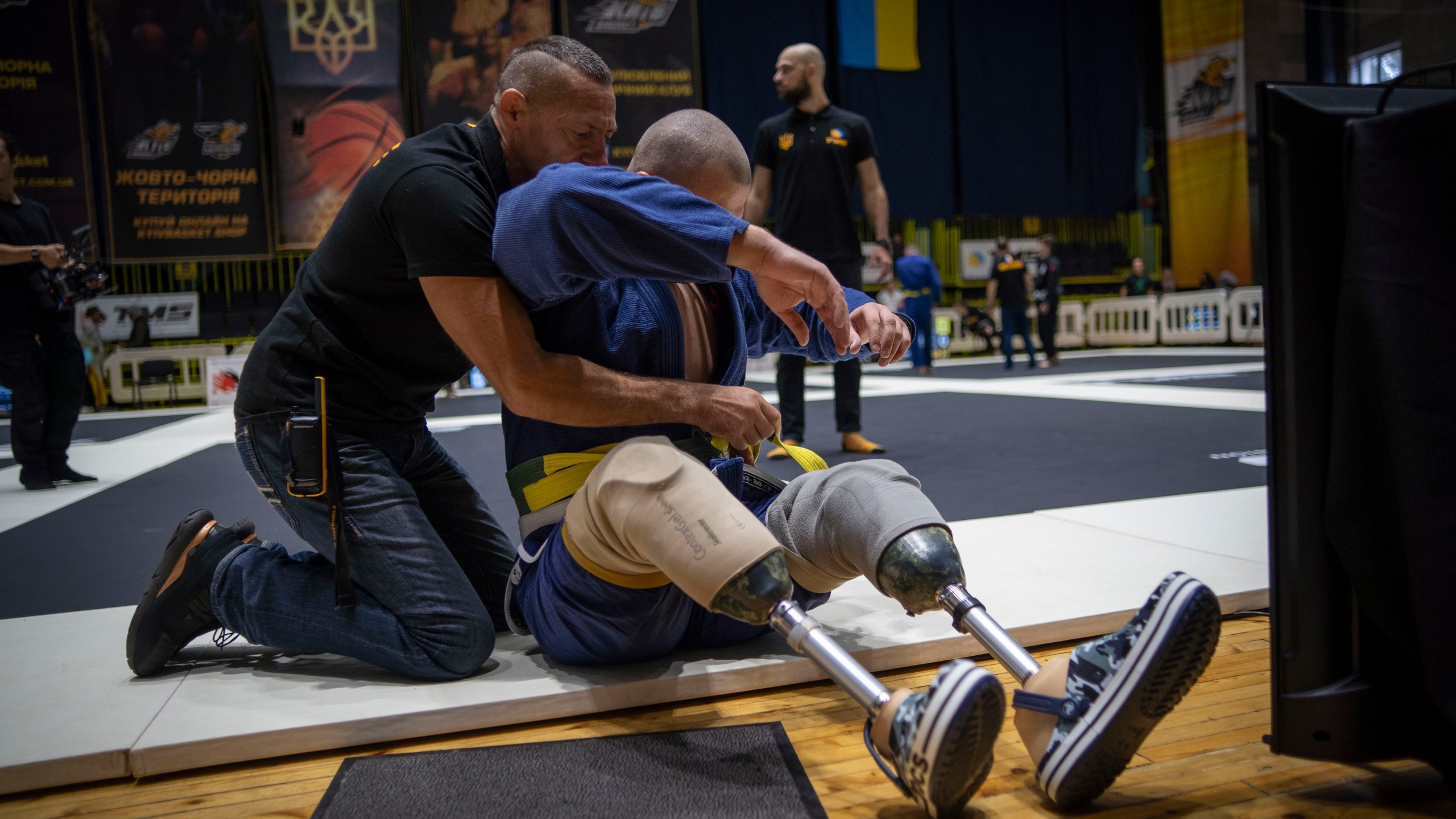 26-year-old Vasyl Oksyntiuk, right, Ukrainian war veteran receives help of tying the belt of his kimono during Ukrainian national competition of jiu jitsu in Kyiv, Ukraine, Sunday, Oct. 29, 2023. More than 20,000 people in the Ukraine have lost limbs from injuries since the start of the Russian war, many of them soldiers. Some of them have learned to deal with their psychological trauma by practicing a form of Brazilian jiu-jitsu. (AP Photo/Hanna Arhirova)