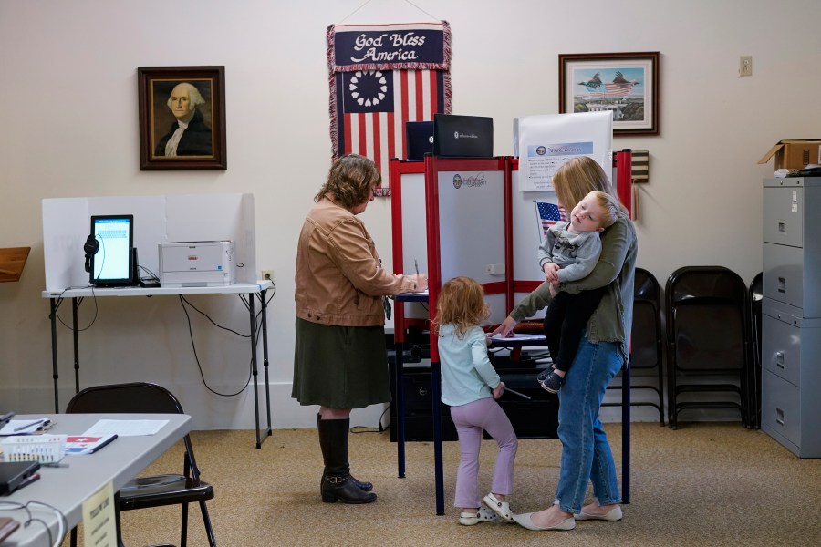 Lauren Miracle, right, holds her son Dawson, 1, as she helps her daughter Oaklynn, 3, fill out a child's practice ballot before voting herself at a polling location in the Washington Township House in Oregonia, Ohio, Tuesday, Nov. 7. Polls are open in a few states for off-year elections that could give hints of voter sentiment ahead of next year's critical presidential contest. (AP Photo/Carolyn Kaster)